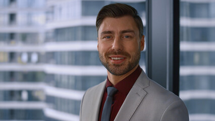Thinking caucasian businessman smiling looking camera in modern window office.