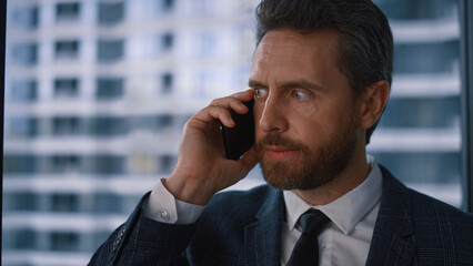 Serious adult boss businessman talking phone calling mobile in modern office.
