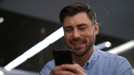 Smiling businessman texting phone chatting online in corporate company workplace