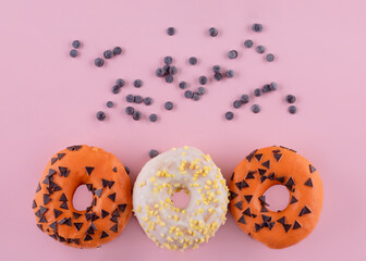 orange and yellow sprinkled  donuts on a pink background  Halloween Space for text