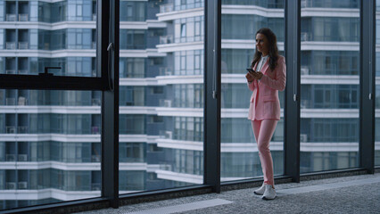 Boss woman using phone reading message surfing internet in office building.