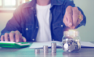 Male businessman hands holding coins placed in a glass jar, bookkeeping concept save money and investment.