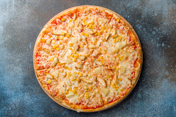 pizza Hawaiian with pineapple and chicken with cheese and corn top view on dark blue stone table
