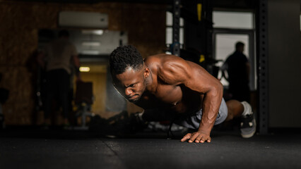 Fototapeta na wymiar African american man doing one arm push ups in the gym. 