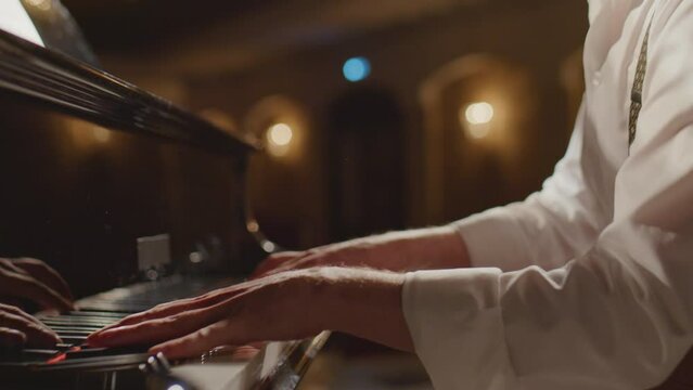 Close up shot of unrecognizable musician playing piano on stage
