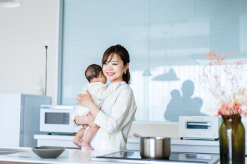 Obraz na płótnie Canvas 赤ちゃんを抱っこしながら家事をする若い女性