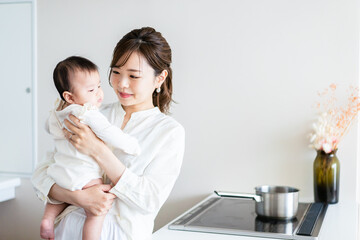 赤ちゃんを抱っこしながら家事をする若い女性