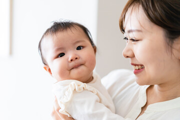 赤ちゃんを抱っこしながら家事をする若い女性