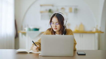 Young asian woman wearing glasses and headset working on computer laptop at house. Work at home, Video conference, Video call, Student learning online class