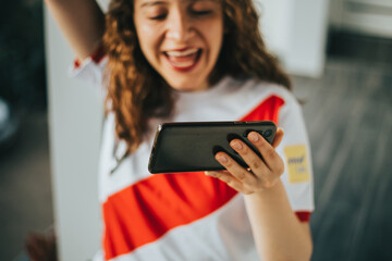 Plano cerrado de mujer celebrando mirando su teléfono. Concepto de gente y reacciones, deporte. © artrolopzimages