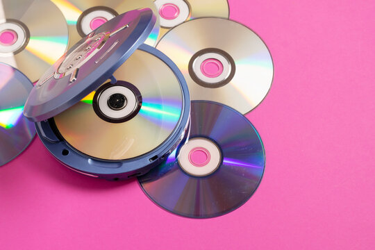 Personal compact portable CD player discs bright pink background. Top view