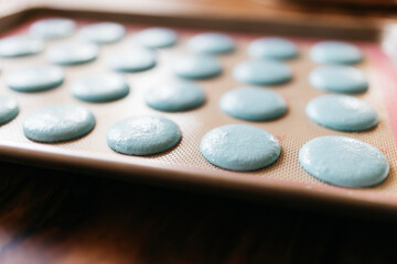 Obraz na płótnie Canvas Bakery. Making macaroons. Blue macarons ready for baking lie on a tray on a wooden table. Biscuit