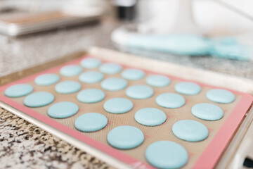 Bakery. Making macaroons. Blue macarons ready for baking lie on a tray on a wooden table. Biscuit