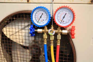 A manifold gauge to check the pressure inside the system to normalize the refrigerant charge during high temperatures and hot old condensing outdoor unit - obrazy, fototapety, plakaty