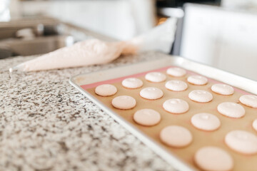 Bakery. Making macaroons. Pink macarons ready for baking lie on a tray. Biscuit. Kitchen background