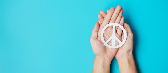 International Day of Peace. Hands holding white paper Peace symbol on blue background. Freedom,...