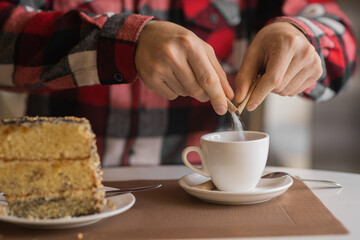 close-up of a businessman's hand with coffee in a cafe, pour sugar from a stick into a cup of espresso, morning coffee