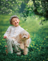 Young boy kid and his dog poodle on the grass together. Happy child hugging his pet smiling with his eyes closed.