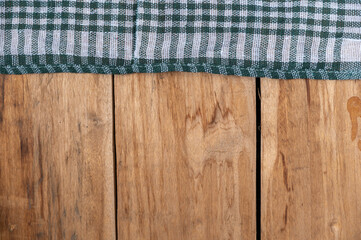 A green checkered cloth lies against a wooden background. A towel or kitchen napkin on the rough...