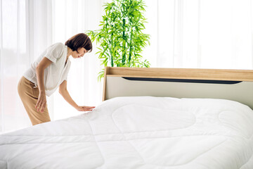 Young asian woman housewife clean bed and set up changing bedsheet with white clean sheet tidy up...