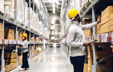 Portrait two african american engineer team shipping order detail on tablet check goods and supplies on shelves with goods inventory in factory warehouse.logistic industry and business export