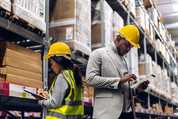 Portrait two african american engineer team shipping order detail on tablet check goods and supplies on shelves with goods inventory in factory warehouse.logistic industry and business export