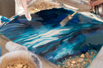 Drying paint in blue color with a hairdryer on the board. Female hand holds a manual gas burner,...