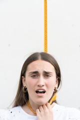 Portrait of teenager girl hanging and asphyxiating with measuring tape.Anorexia, eating disorders and social pressure on woman figure concept. - obrazy, fototapety, plakaty
