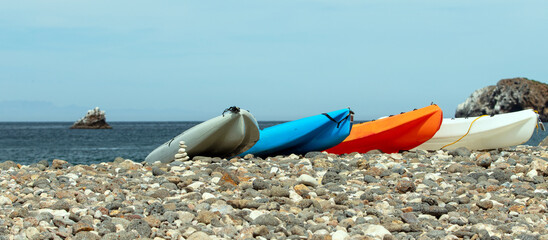 Kayaks pulled ashore on Scorpion bay rocky beach on Santa Cruz island in the Channel Islands National Park offshore from Ventura California United States