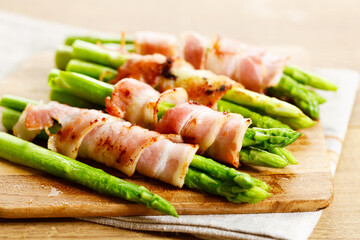 Bacon wrapped asparagus on wooden plate.