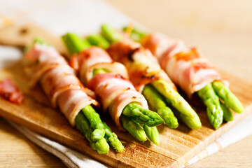 Bacon wrapped asparagus on wooden plate.