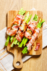 Bacon wrapped asparagus on wooden plate.