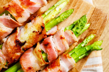 Bacon wrapped asparagus on wooden plate.