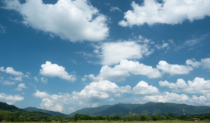 The white clouds have a quaint and rural shape. The sky is cloudy and blue