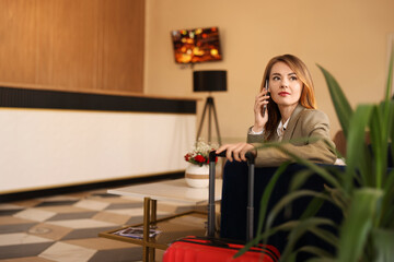 Obraz na płótnie Canvas Beautiful woman talking on phone while waiting in hotel hall