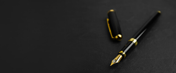 Beautiful fountain pen with ornate nib on black table, closeup view with space for text. Banner design - Powered by Adobe
