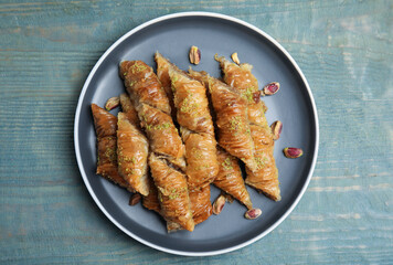 Delicious baklava with pistachio nuts on light blue wooden table, top view