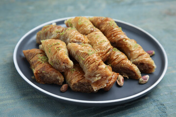 Delicious baklava with pistachio nuts on light blue wooden table, closeup