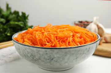 Delicious Korean carrot salad in bowl on white wooden table