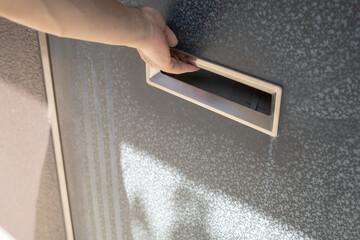 玄関の郵便受けを開ける手