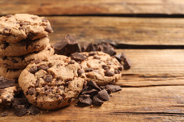 Many delicious chocolate chip cookies on wooden table. Space for text