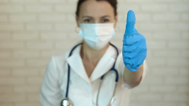 Good luck in the doctor treatment. A pretty happy doctor in protective uniform show thumb up because of her good work.