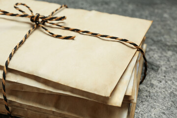 Stack of old letters tied with string on grey table, closeup