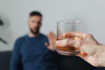 Man refusing to drink whiskey indoors, closeup. Alcohol addiction treatment