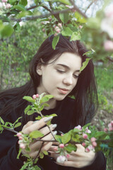 Pretty  teen girl are posing in garden near blossom apple tree with pink flowers.