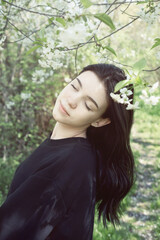 Pretty  teen girl are posing in garden near blossom apple tree with pink flowers.
