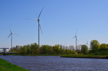 Beautiful view of countryside with river and wind turbines on sunny day. Alternative energy source