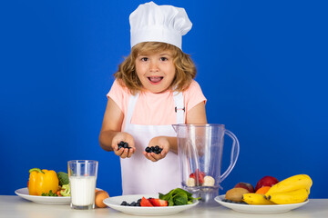 Excited funny chef cook. Child chef dressed cook baker apron and chef hat cooking blueberries smoothie isolated on studio background. Healthy nutrition kids food.