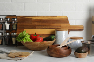 Different cooking utensils and fresh vegetables on countertop in kitchen