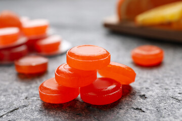 Many orange cough drops on grey table, closeup